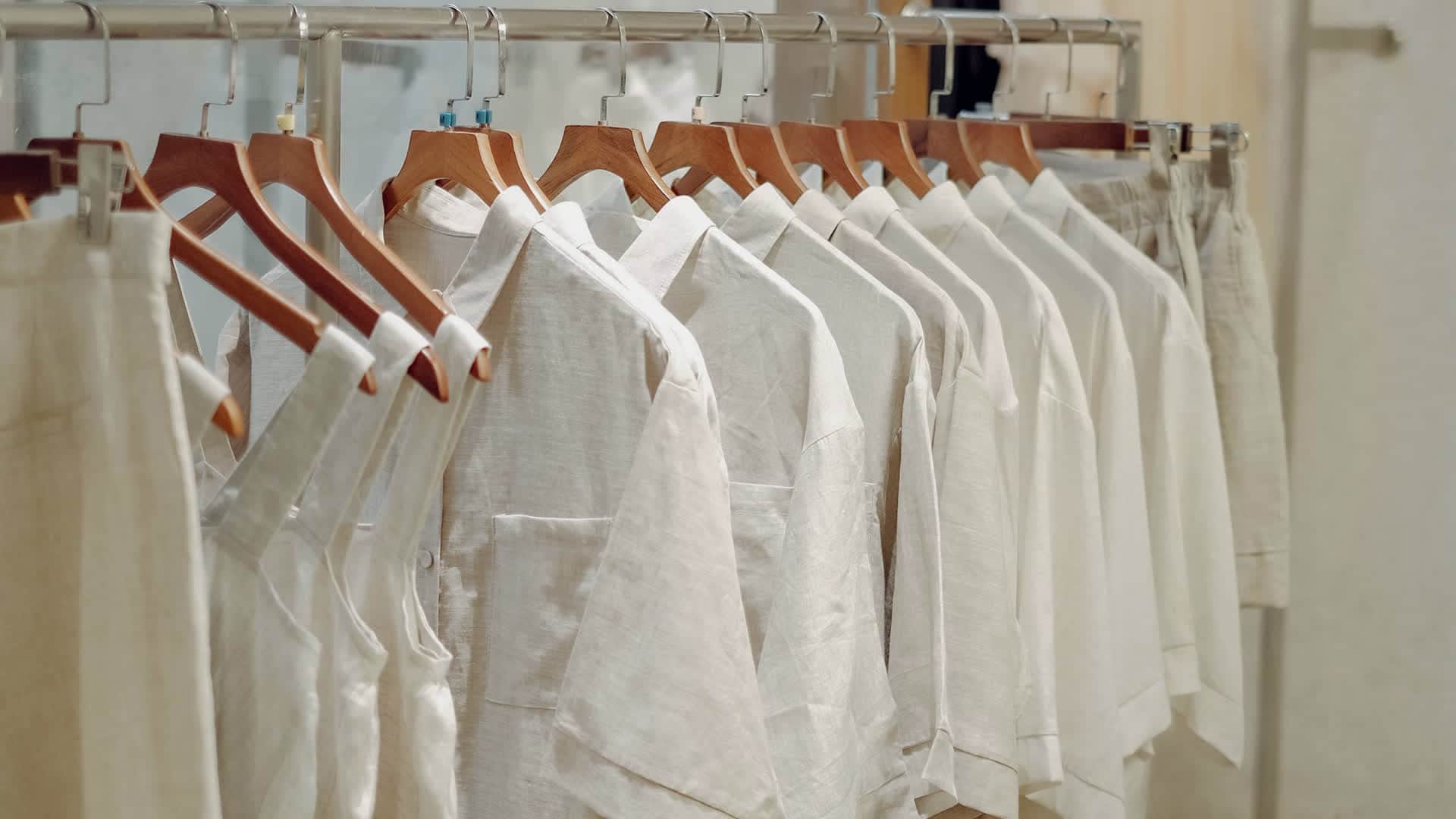 A wide, high-ceilinged stockroom with garment racks and storage boxes along the walls